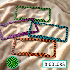 May include: Several license plate frames with checkered patterns in various colors, including green, purple, blue, and orange. The frames are rectangular with rounded corners and mounting holes. The image also includes a graphic that says "8 COLORS".