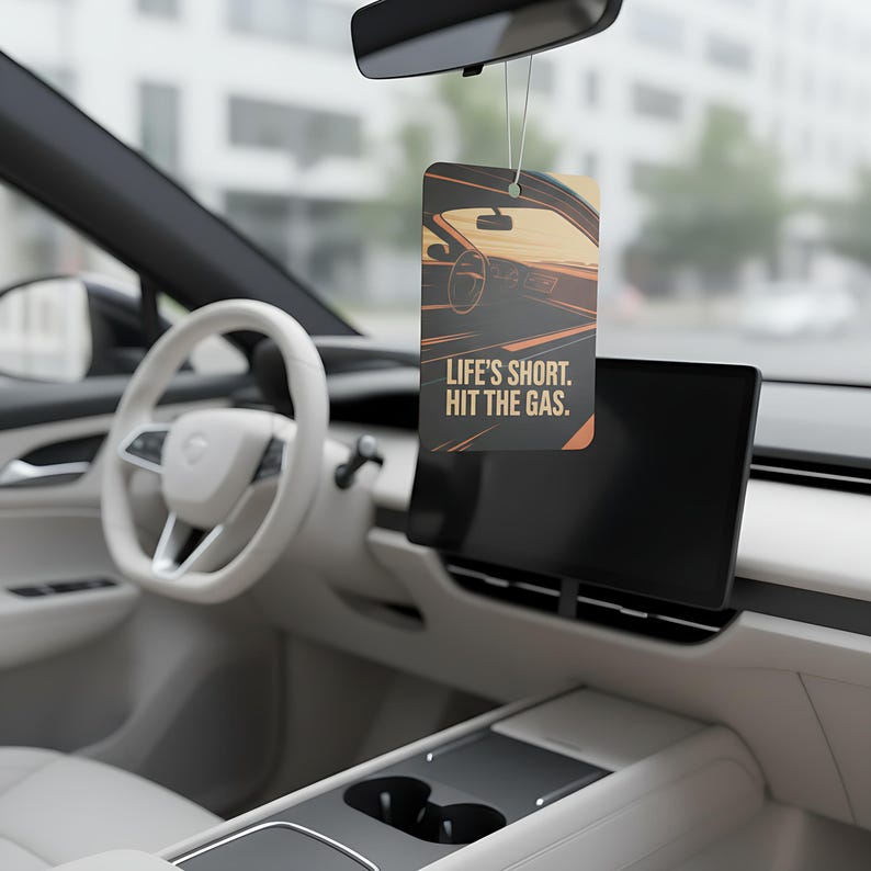 May include: Rectangular car air freshener with a graphic of a car interior in shades of orange and brown. The text "LIFE'S SHORT. HIT THE GAS." is printed on the front. The air freshener hangs from a string in a car interior.