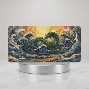 May include: License plate with a green dragon design amidst ocean waves. The dragon is depicted in a curled pose. The background features a sunset with orange and yellow tones. The waves are blue and white.