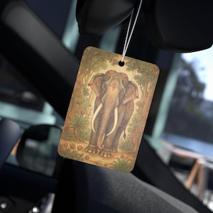 May include: Rectangular car air freshener featuring an illustration of an elephant with long tusks, set against a backdrop of trees and foliage. The air freshener is suspended by a white string, showcasing a detailed, artistic design.