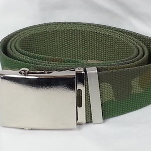 Puede incluir: Un cinturón de tela de camuflaje verde con una hebilla de metal plateado.