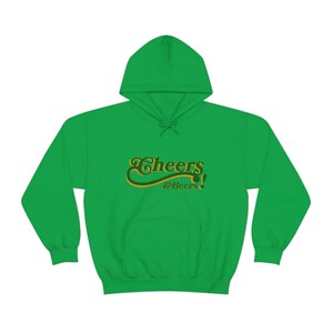 May include: Green hooded sweatshirt with a gold and green "Cheers & Beers!" graphic.