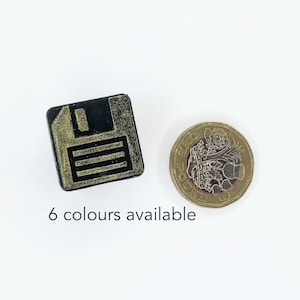 Op de afbeelding: Een klein zwart vierkant houten blokje met een gouden floppy disk-icoon. Het blokje ligt naast een Britse munt van één pond ter groottevergelijking. 6 kleuren beschikbaar.