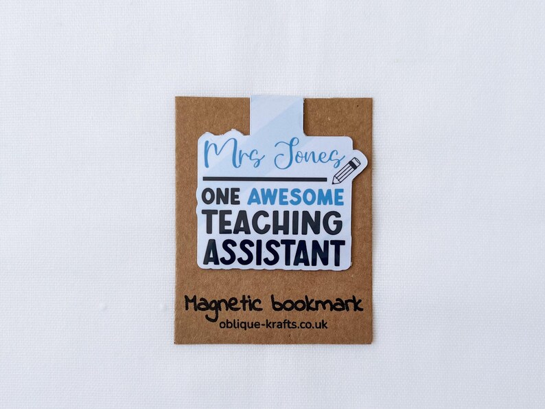 May include: A magnetic bookmark with the text "Mrs Jones ONE AWESOME TEACHING ASSISTANT" in blue and black. The bookmark has a pencil graphic and is on a brown card with the text "Magnetic bookmark" and a website address.