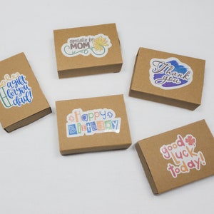 May include: Five small, brown cardboard gift boxes with colourful stickers. The stickers read: "A gift for you dad!", "Especially for MOM", "Happy Birthday", "Thank you", and "Good luck today!"