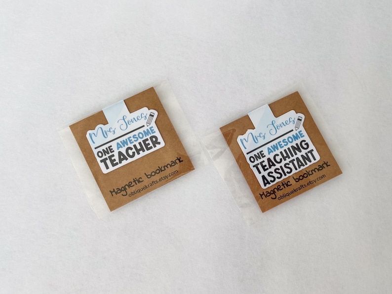 May include: Two magnetic bookmarks in clear packaging. Each bookmark has a brown background with the text "Mrs. Jones" and "ONE AWESOME TEACHER" or "ONE AWESOME TEACHING ASSISTANT". The bottom of the bookmark reads "Magnetic bookmark obliquekrafts.etsy.com".
