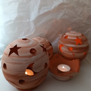 Handmade ceramic candle holder in the shape of a ball, decorated with stars, and a saucer for candles or incense tablets.