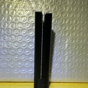 May include: A black plastic pipe with a split at the top and a textured bottom.