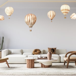 May include: A white sectional sofa with brown throw pillows, a wooden coffee table, and a brown armchair. The wall behind the furniture is decorated with brown and white hot air balloons.