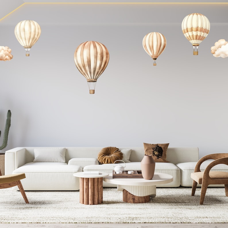May include: A white sectional sofa with brown throw pillows, a wooden coffee table, and a brown armchair. The wall behind the furniture is decorated with brown and white hot air balloons.