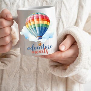 May include: White ceramic mug with a colorful hot air balloon graphic and the text "adventure awaits" in blue and red lettering.