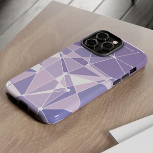 May include: A purple and white geometric phone case with a camera cutout. The case has a modern, abstract design.