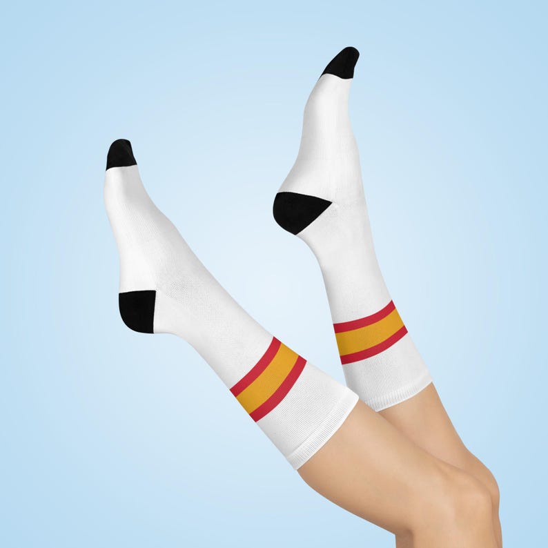 May include: A pair of white socks with red and yellow stripes. The socks are being worn on a person's legs, with the feet pointing upwards.