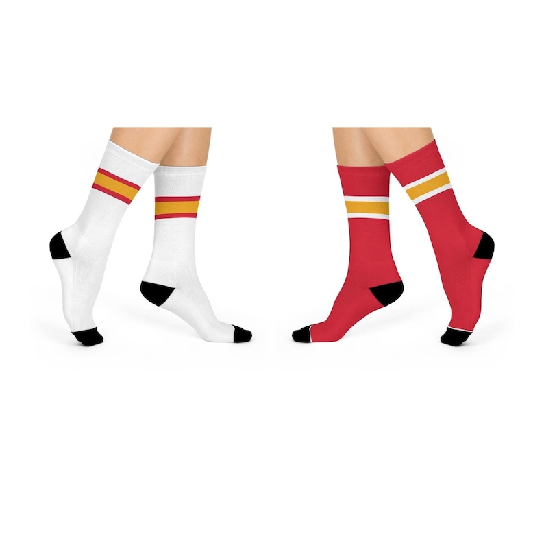 May include: Two pairs of socks with a red and yellow stripe design. One pair is white with a red stripe and a yellow stripe. The other pair is red with a yellow stripe and a white stripe.