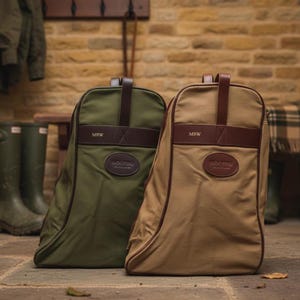 May include: Two canvas backpacks, one olive green and one tan, with brown leather accents. Each bag features a top handle, a leather patch with a logo, and the initials "MRW". The bags are designed for outdoor use.