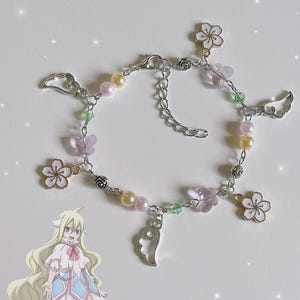 May include: A silver charm bracelet with pink, white, and green charms. The charms include flowers, wings, and beads.