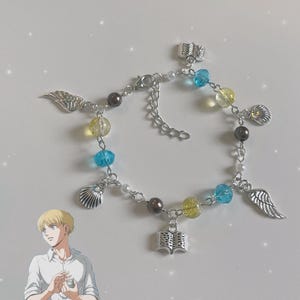 May include: A silver charm bracelet with blue, yellow, and white beads. The charms include a book, wings, and seashells.