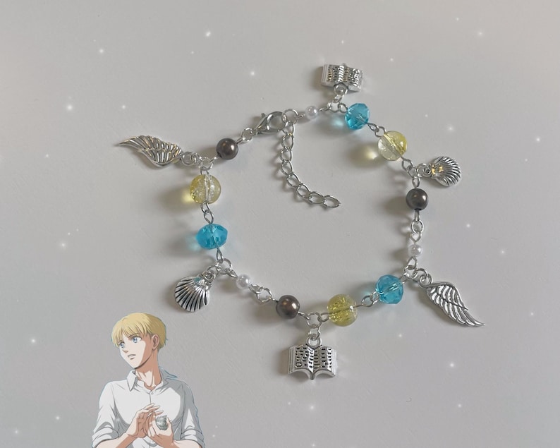 May include: A silver charm bracelet with blue, yellow, and white beads. The charms include a book, wings, and seashells.
