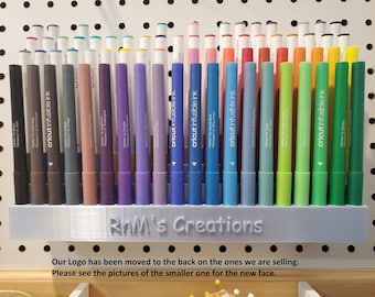 May include: A set of 30 Cricut Infusible Ink markers in a variety of colours, organised in a white plastic holder. The holder has the text "RnM's Creations" printed on the front.