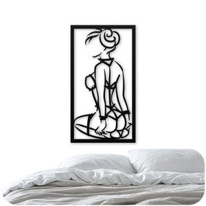 Puede incluir: Decoraci&oacute;n de pared de arte de l&iacute;nea en blanco y negro con una mujer en lencer&iacute;a. La mujer se representa en una pose de rodillas con la espalda al espectador. La obra de arte est&aacute; enmarcada en un rect&aacute;ngulo negro.