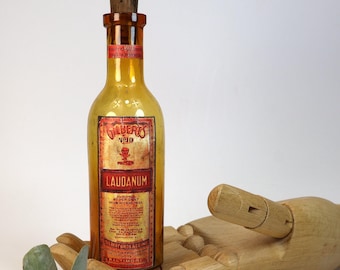 Small, old, empty amber glass pharmacy or apothecary bottle with a decorative "Poison LAUDANUM" design