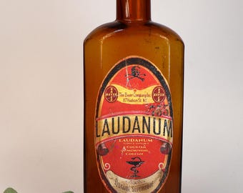 Antique and empty amber glass pharmacy or apothecary bottle with a decorated "Laudanum" label