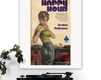 Op de afbeelding: Een ingelijste print van een vintage boekomslag getiteld "Happy Hour". De illustratie toont een vrouw in een groene top en geruite rok die een cocktail vasthoudt. De cover bevat tekst over stijl en winnen, met de naam van de auteur en "First Printing Anywhere."