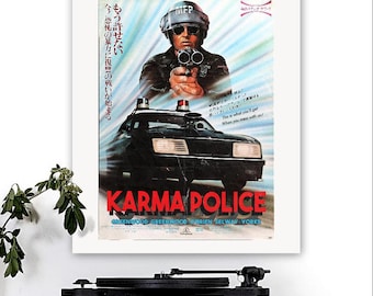 May include: A framed movie poster for "Karma Police" featuring a police officer aiming a gun, a black police car, and Japanese text. The poster has a blue and red color scheme with the title in large red letters.