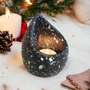 May include: A black and white speckled teardrop-shaped candle holder with a small white candle inside.