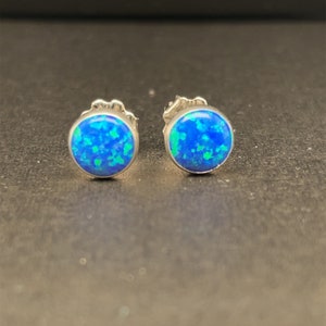 May include: A pair of silver stud earrings with blue and green opal stones.