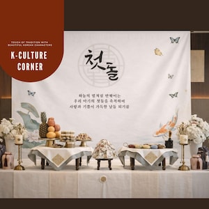 May include: A Korean traditional first birthday celebration setup. The scene includes tables with food, floral arrangements, and a backdrop with Korean characters and text. The words "K-CULTURE CORNER" are visible.