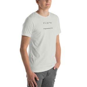 May include: A light-colored t-shirt with the formula F = m * a and the words "Programming Force" printed in black. The shirt is a short-sleeved crew neck.