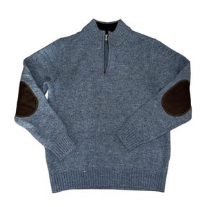 May include: A blue sweater with a quarter-zip neckline and brown elbow patches. The sweater has a ribbed hem and cuffs. The material appears to be a knit fabric. The zipper is silver.