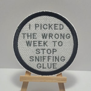May include: A white round patch with a black border and the text "I picked the wrong week to stop sniffing glue" in gray.