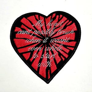 Può includere: Toppa ricamata a forma di cuore con un design rosso e nero. L'interno rosso presenta un motivo radiale e il bordo nero incornicia il cuore. Il testo bianco in corsivo recita: "My heart can't possibly break when it wasn't even whole to start with."