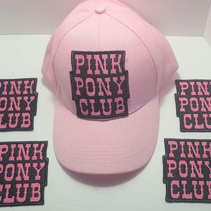 May include: Pink baseball cap with a black patch that says "PINK PONY CLUB" on the front. There are four additional patches with the same text on a white background.