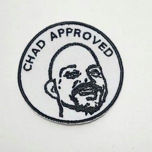 May include: A white, circular patch with a black border. The patch features a black and white illustration of a smiling face with a beard. The words "CHAD APPROVED" are printed in a black, curved font around the face.