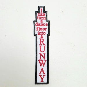 May include: Embroidered patch with the text "I can turn a dance floor into a RUNWAY" in red lettering. The patch has a white background with a black border, and a rectangular shape.