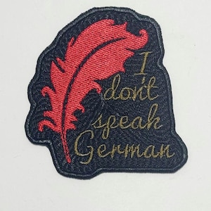 Puede incluir: Parche bordado con fondo negro y diseño de pluma roja. El parche dice "I don't speak German" en letras doradas. El parche tiene un borde negro.