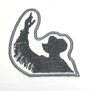 May include: Embroidered iron-on patch featuring a black silhouette of a cowboy tipping his hat, with a gray outline.