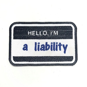 May include: Rectangular patch with a black border and a white center. The text "HELLO, I'M" is at the top, with "a liability" in blue below. The patch is likely for clothing or accessories.