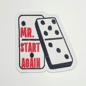 May include: Embroidered patch featuring two dominoes with the text "MR. START AGAIN" in red. The dominoes are white with black borders and black dots. The patch has a white border.