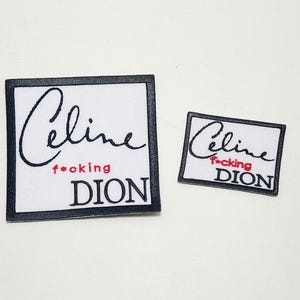 以下が含まれることがあります： 黒い縁取りのある白い布パッチが2つ。大きいパッチには筆記体で「Celine」と赤字で「f*cking」、黒字で「DION」と書かれています。小さいパッチも同様のデザインです。