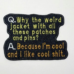 May include: Black embroidered patch with the text "Q. Why the weird jacket with all these patches and pins? A. Because I'm cool and I like cool shit,". The text is in yellow and white.