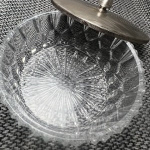 May include: A clear glass bowl with a cut glass design and a silver lid with a knob on top.