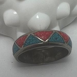 May include: A silver ring with a turquoise and coral inlay design. The ring is set with a geometric pattern of triangles.