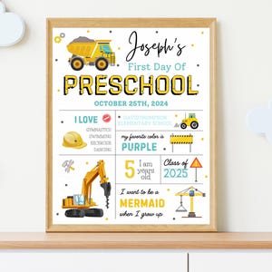 May include: A framed print for a child's first day of preschool. The design features construction vehicles, the text "Joseph's First Day Of Preschool", the date, and other details like favorite color and future aspirations. The color scheme includes yellow, black, and purple.