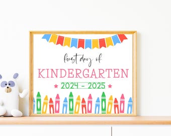 May include: A framed sign with the words "first day of KINDERGARTEN 2024-2025" in pink and green. The sign is decorated with colorful crayon illustrations and a banner. A stuffed animal is on the left.