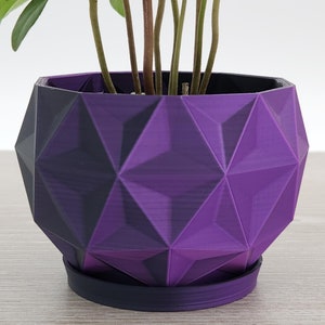 May include: A purple geometric planter with a black base. The planter has a textured, diamond-like pattern.