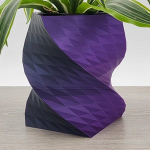 May include: A purple and black geometric planter with a plant growing out of it.